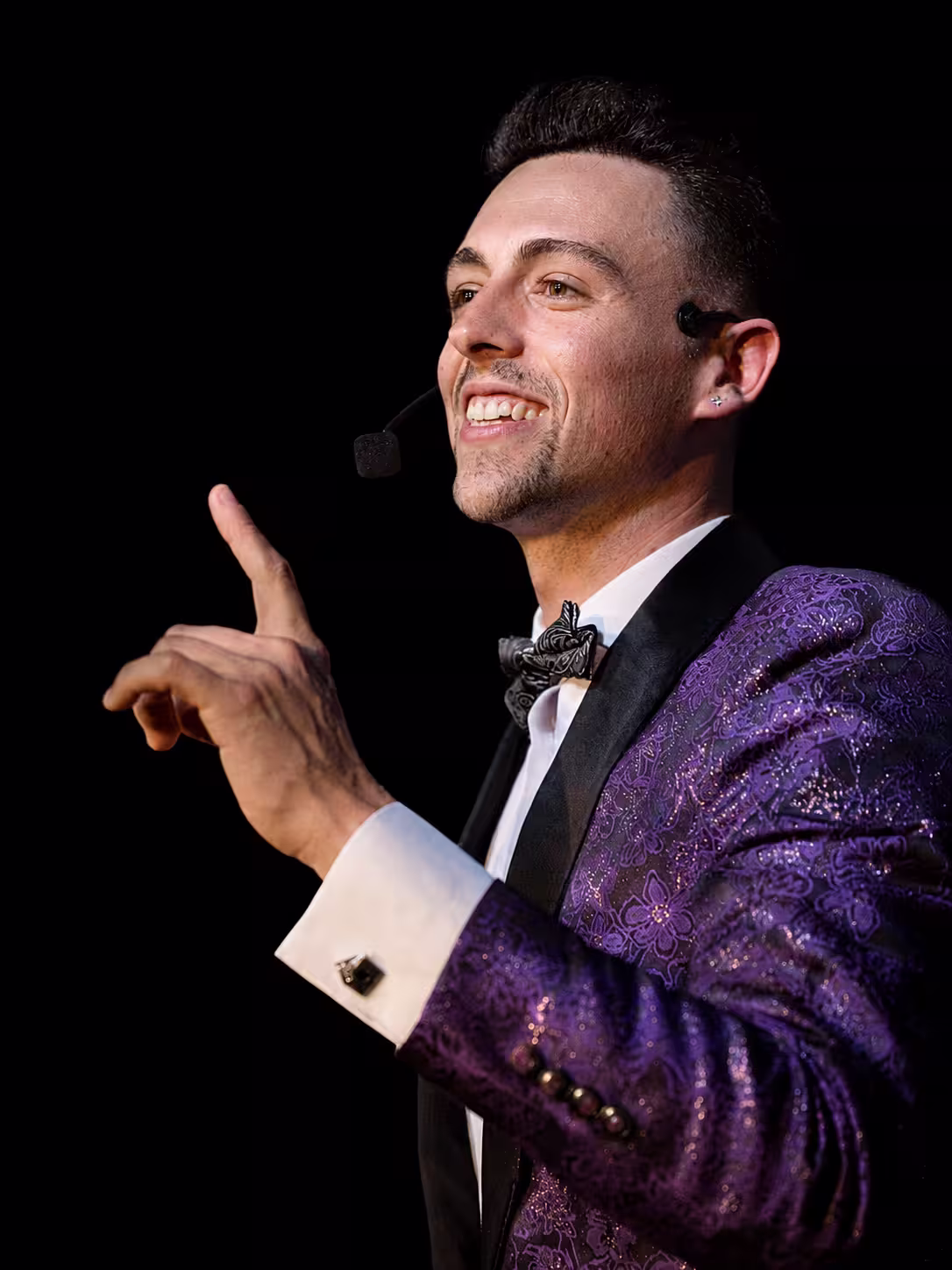 Alexander Main on stage, wearing a headset microphone, during the show